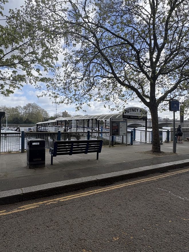 A bench and pier shelter on the empty riverside pavement