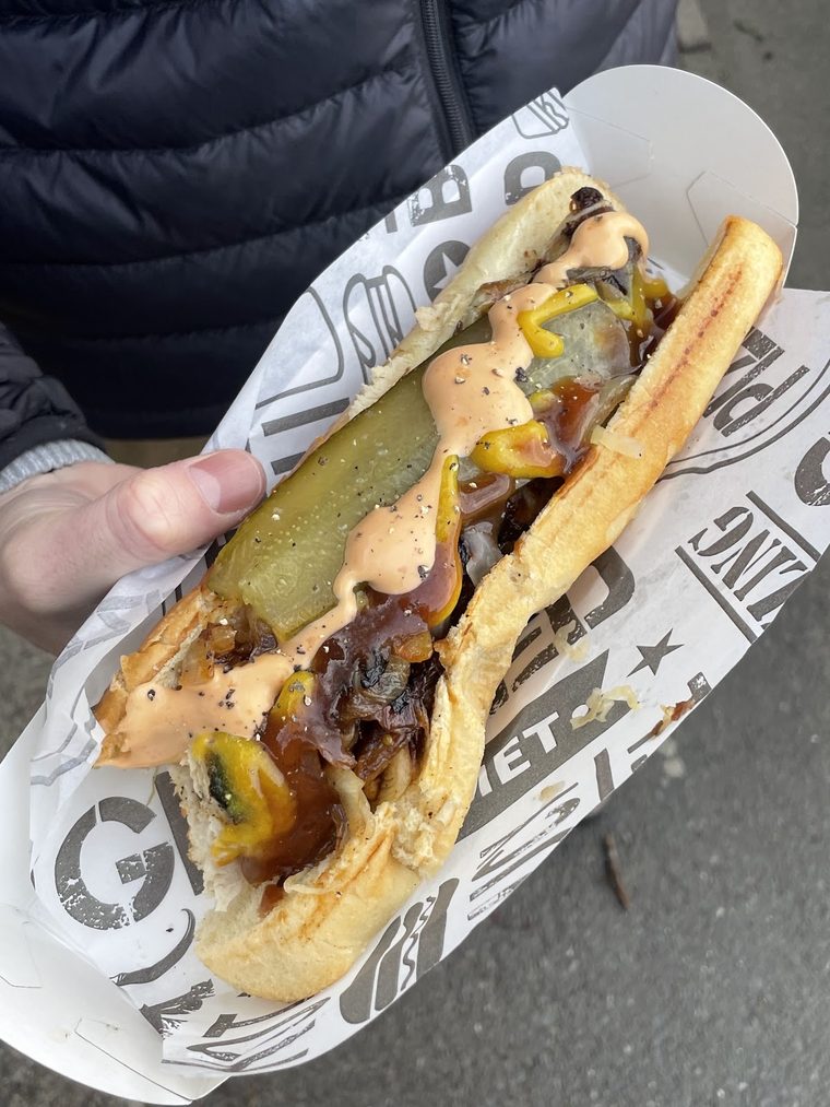 A loaded bratwurst with cheese, onions and gherkin